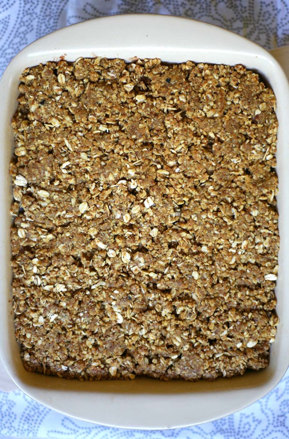 A baking dish with brown crunchy crumble topping nicely flattened into the dish on one layer.