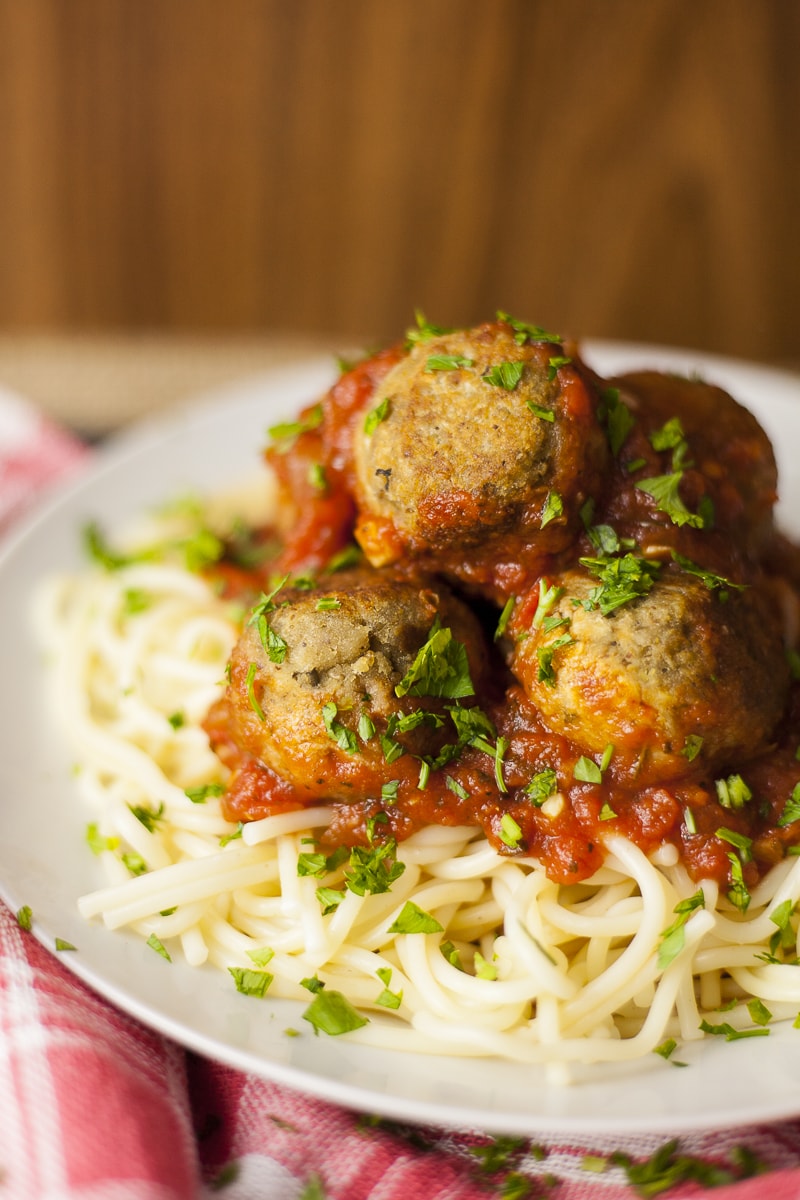 Spaghetti topped with marinara sauce and a couple of eggplant meatballs sprinkled with parsley