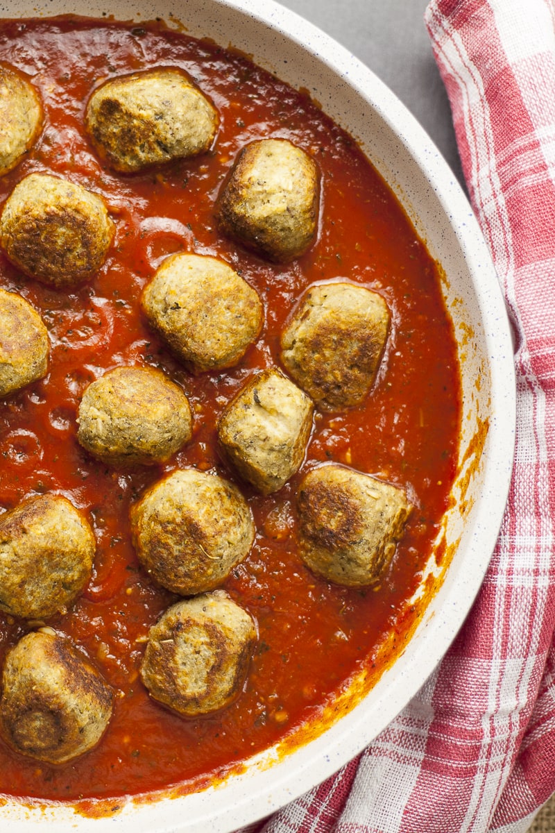 Overlay photo of a frying pan. Lot of small eggplant balls in marinara sauce