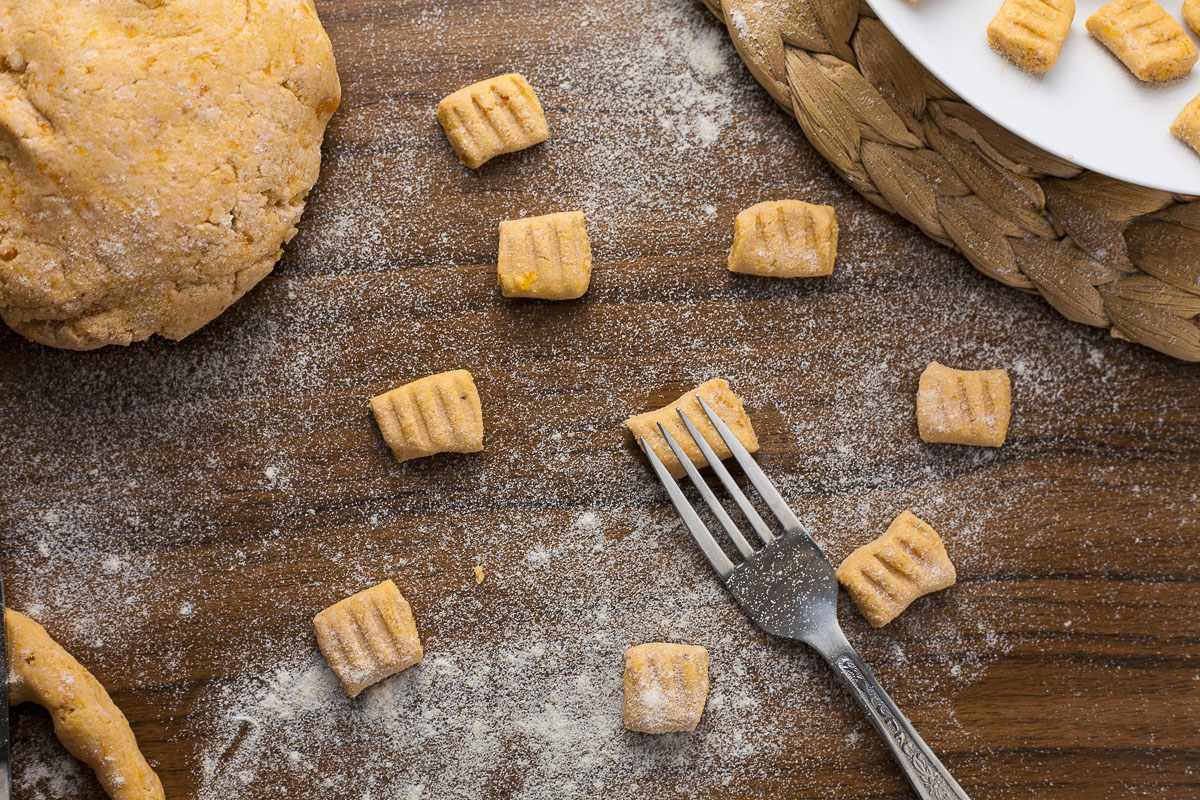 Several soft orange rectangle-shaped pasta with a fork making a dent in one of them. 