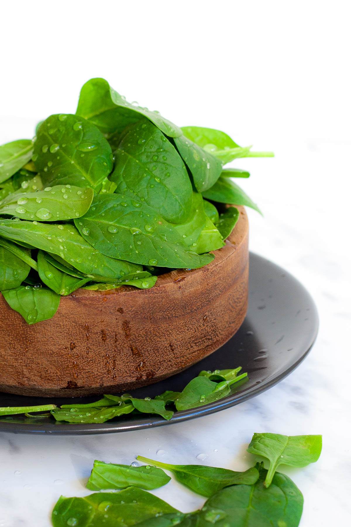 Wooden bowl with spinach leaves freshly washed