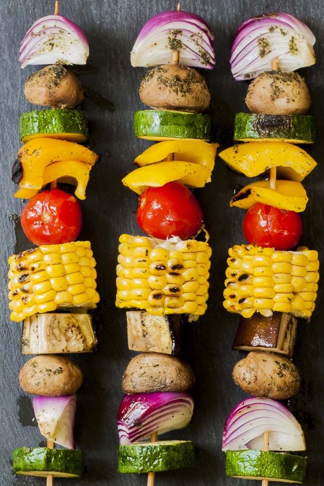 Close-up of 3 veggie skewers on a grey plate