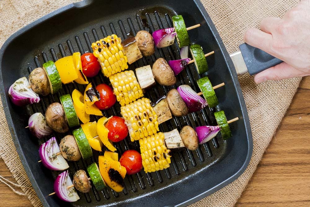 Close-up of 4 vegetable skewers in a grill pan