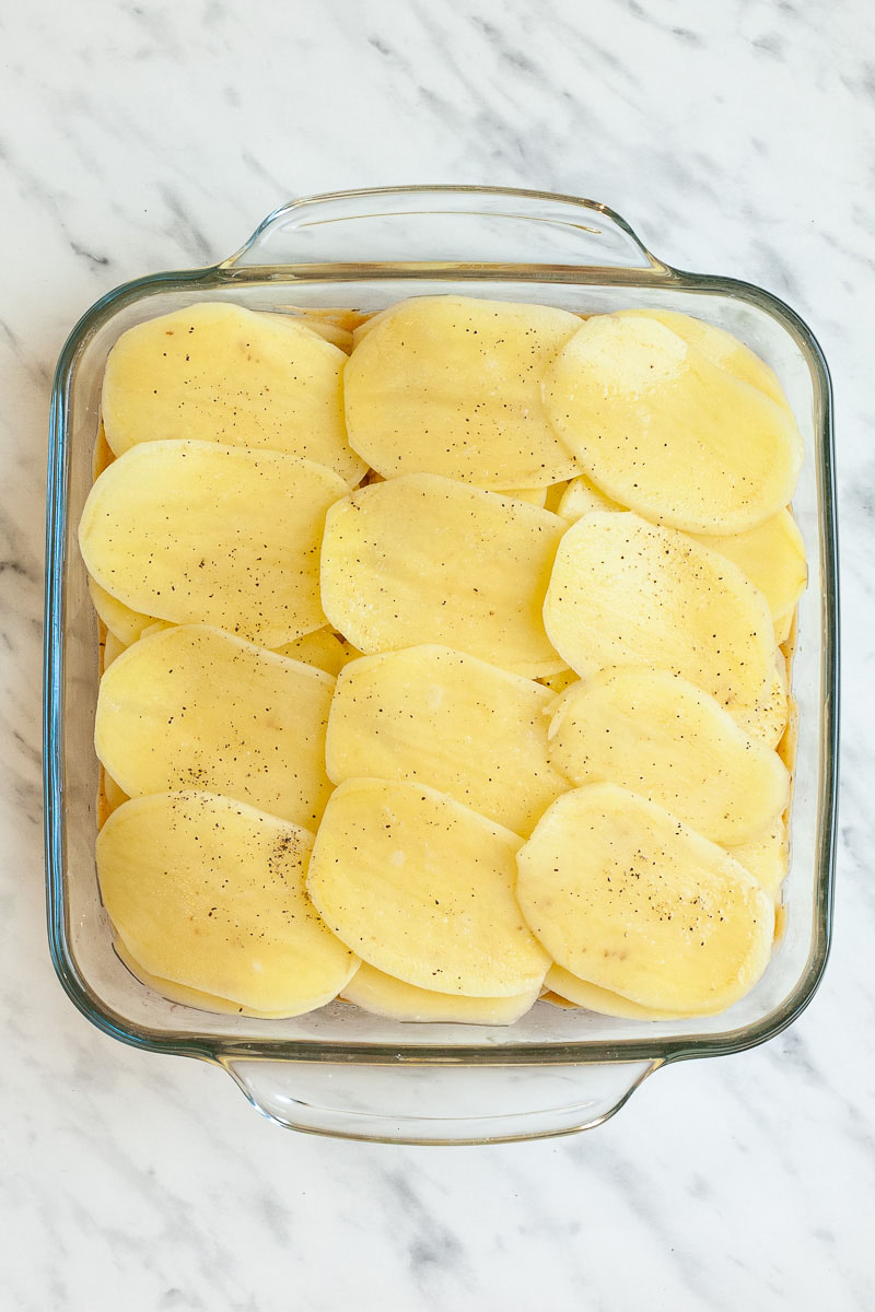 A glass casserole dish with layers of potato slices from above
