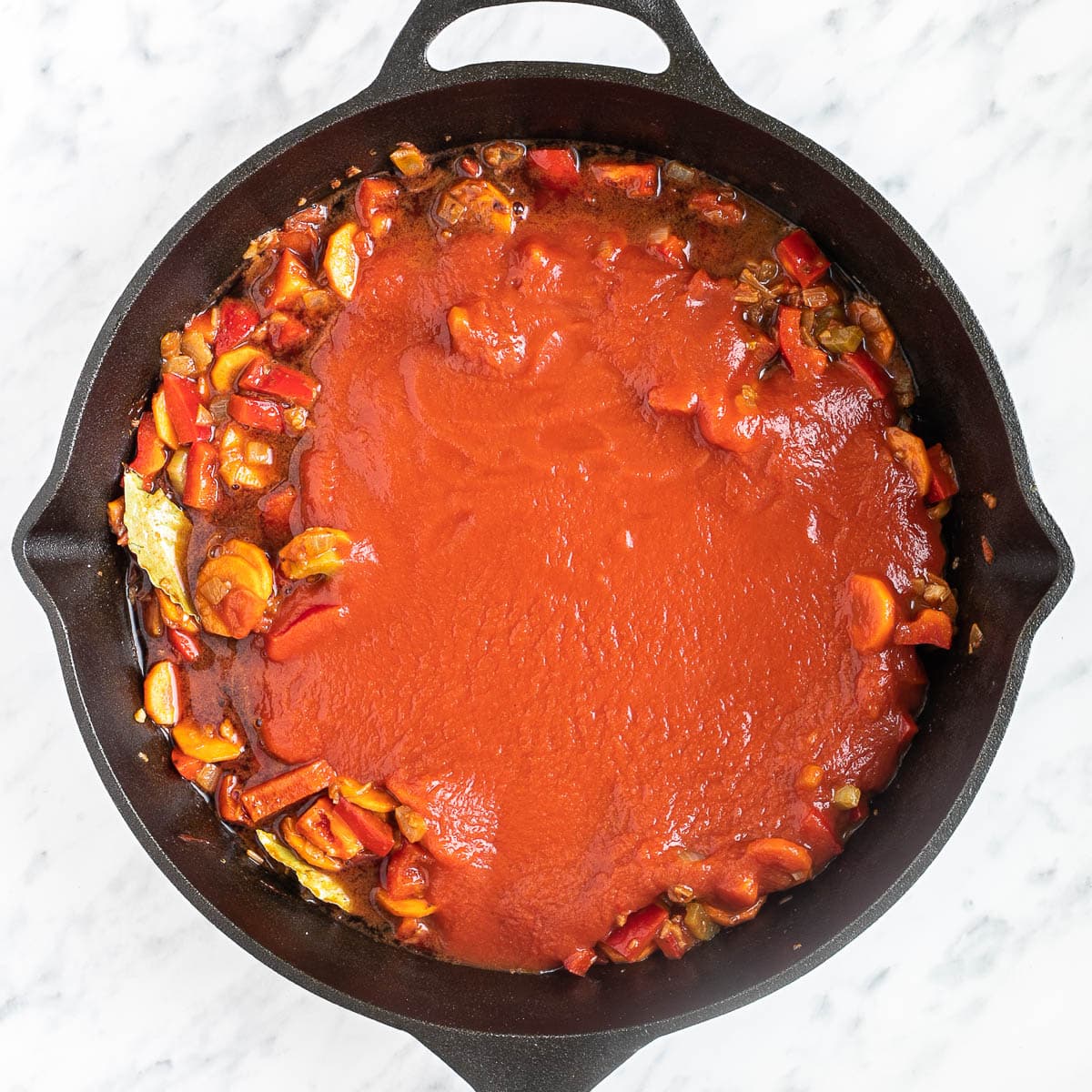 Cast iron skillet with chopped veggies in a thick red tomato sauce.