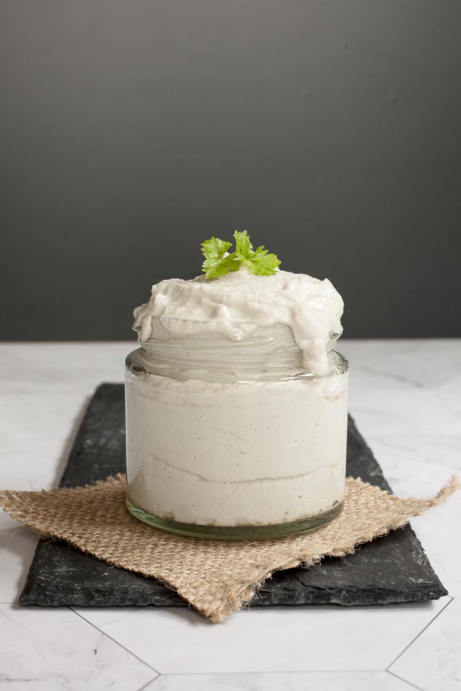 Small white glass packed with dairy-free sour cream and topped with fresh parsley. 