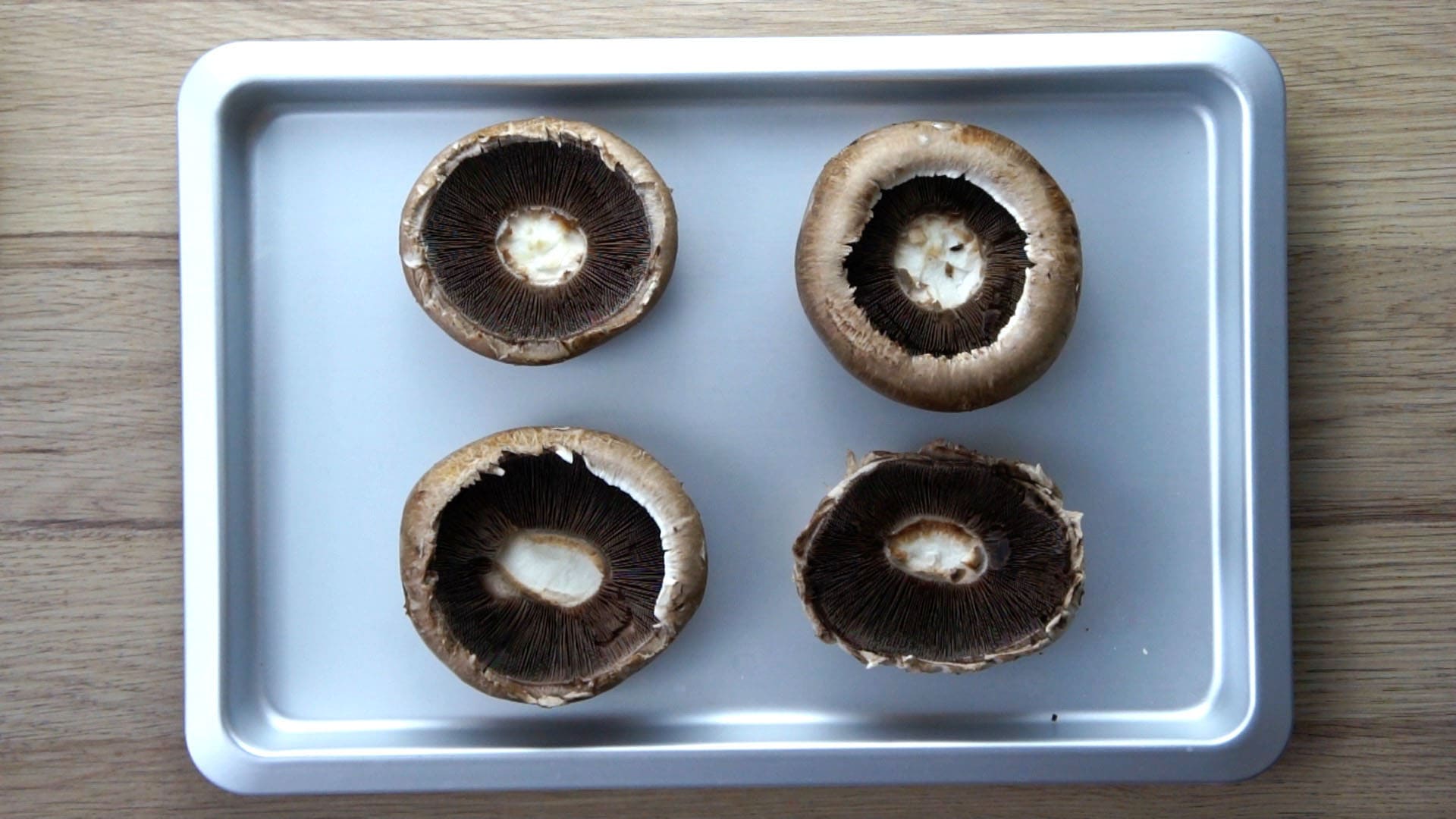 4 large mushroom caps on a baking tray (no stalk) ready to be stuffed