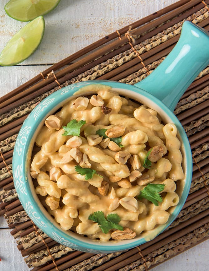 Blue bowl of Thai red curry mac and cheese topped with chopped peanuts and cilantro