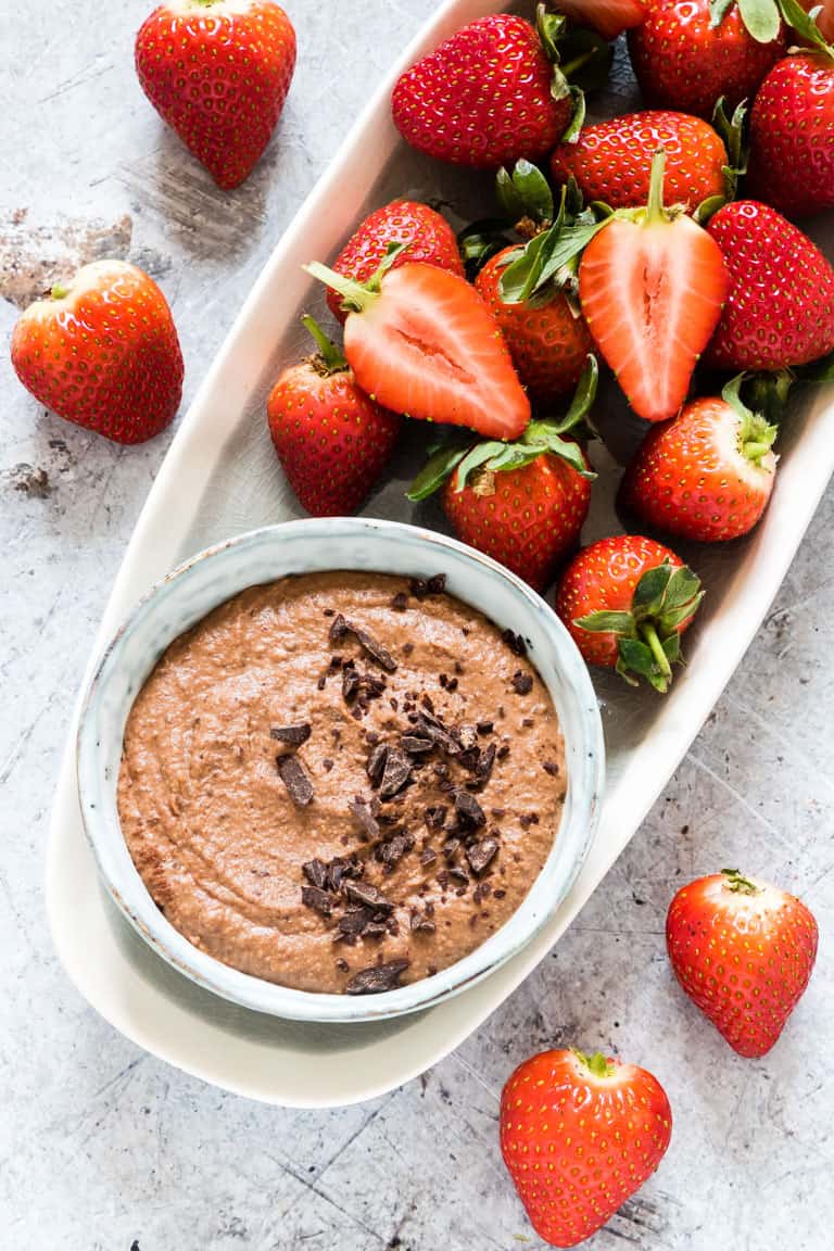 Chocolate hummus in a small bowl with fresh strawberries around