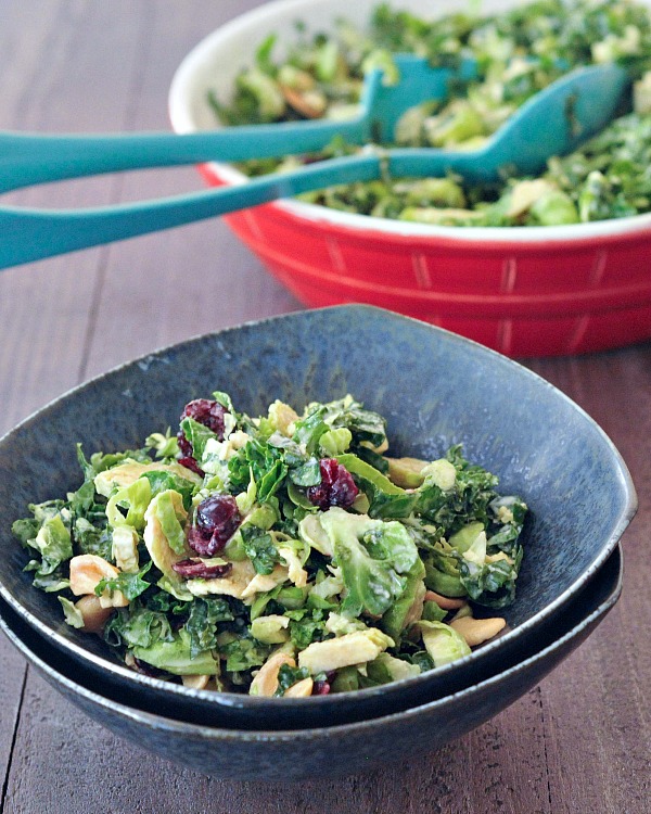 A black salad bowl with bale, cashews and dried cranberries. 