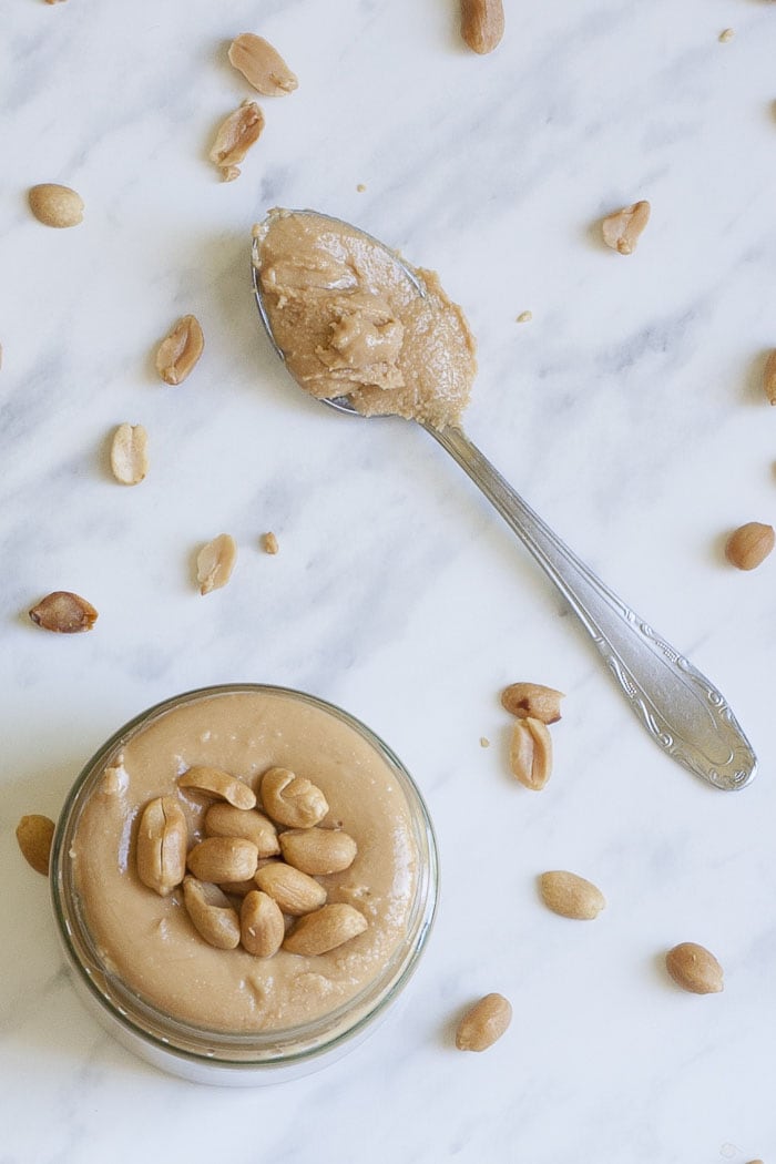 Jar and a spoon of homemade peanut butter from above