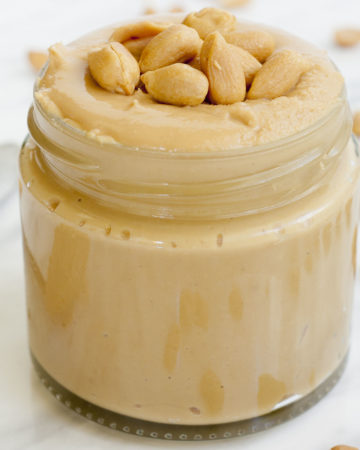 A small jar with light peanut butter topped with chopped peanuts.
