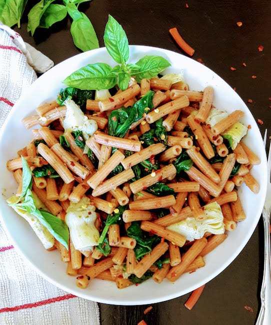 Red-ish sedanini pasta with wilted spinach and artichoke hearts