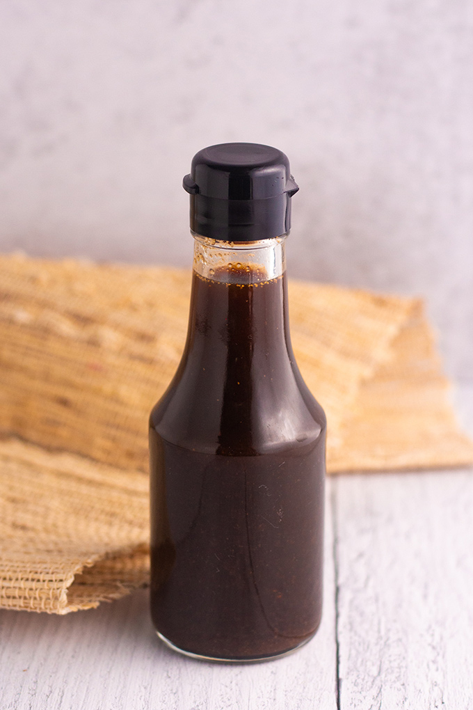 A small bottle of brown liquid with a black cap. 