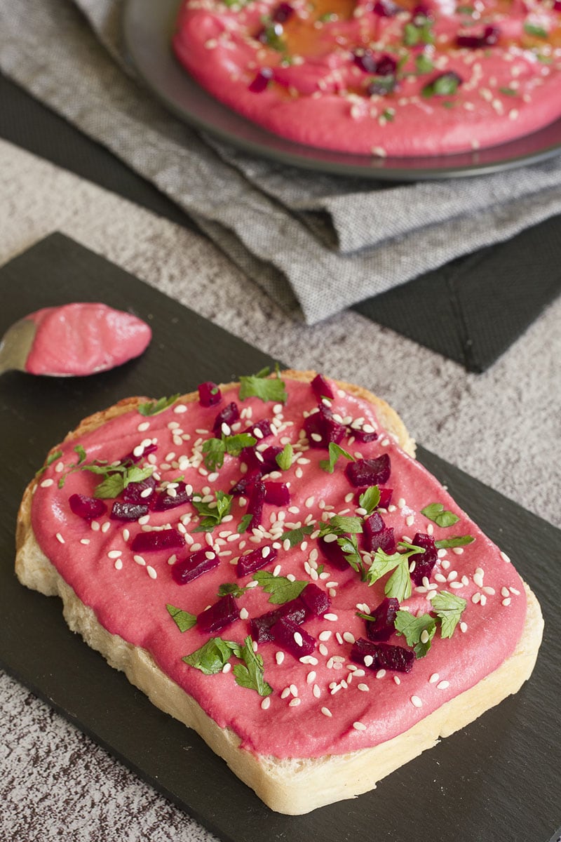 A slice of bread topped with beet hummus spread