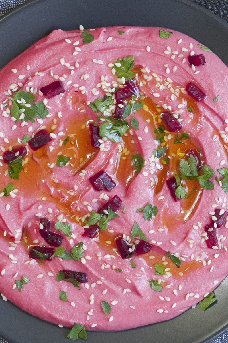 Smooth pink beetroot hummus topped with roasted beets, parsley and sesame seeds