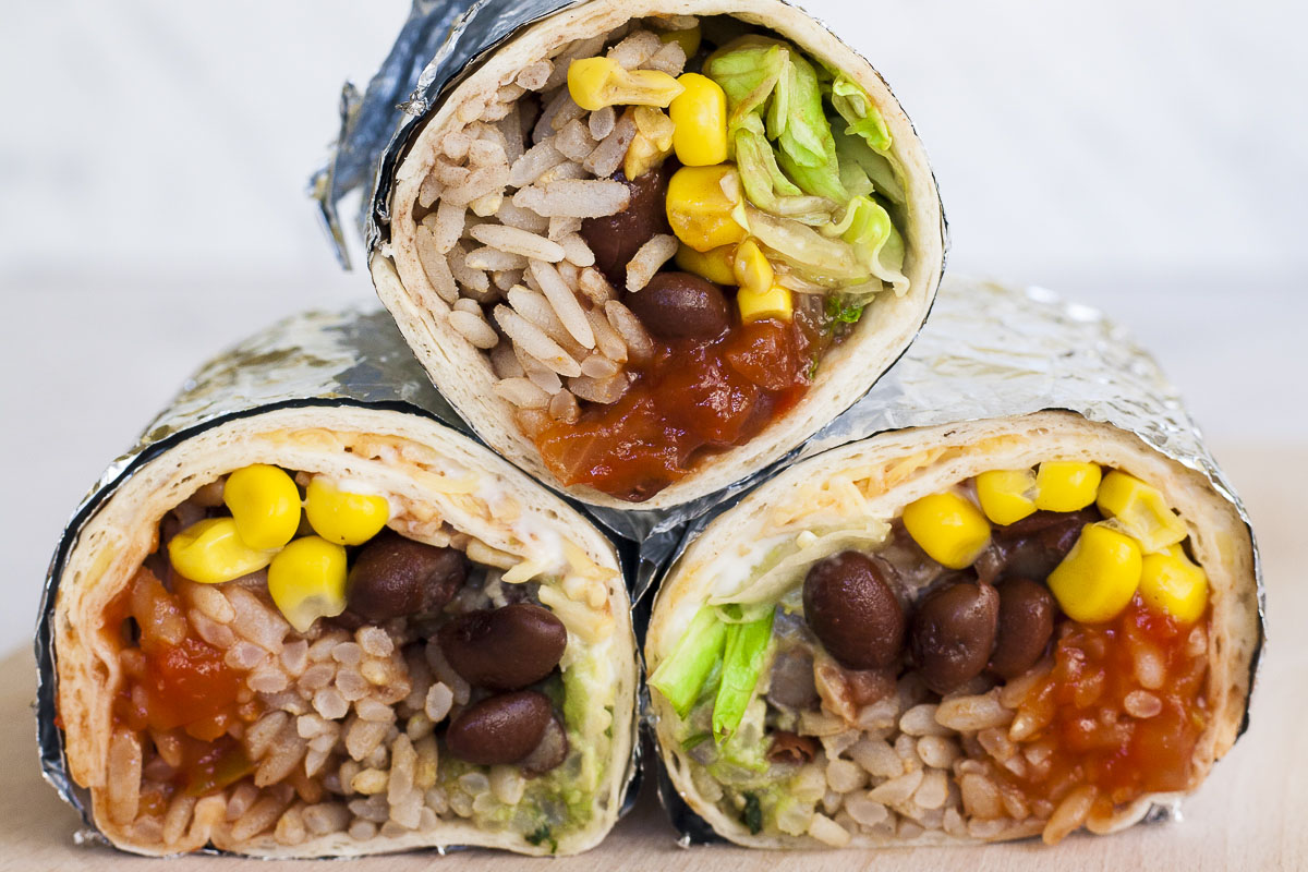 3 rainbow coloured round-shaped rolls wrapped in tin foil. Inside red, yellow, brown, green and white pieces.