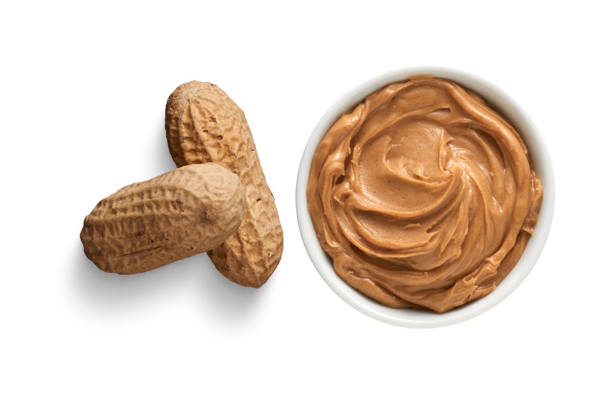 2 peanuts and peanut butter in a small white bowl