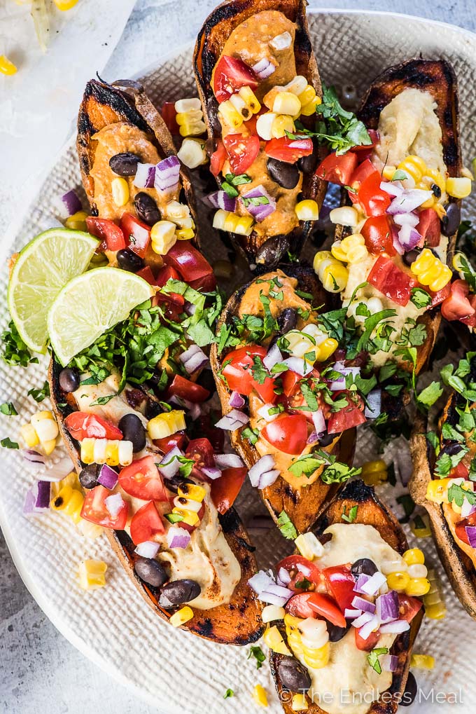 Lots of stuffed sweet potatoes topped with black beans, sweet corn, chopped tomato, freshly chopped green herbs and an orange sauce