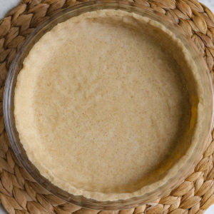 Glass pie pan with brown unbaked pie crust from above