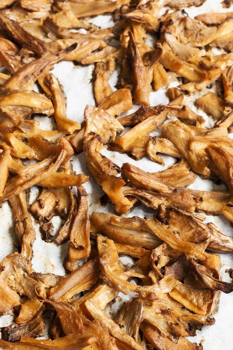 Shredded mushrooms scattered around a white parchment paper