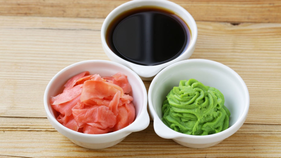 3 small white bowls. One with black liquid, one with pink slices, and one with green paste.