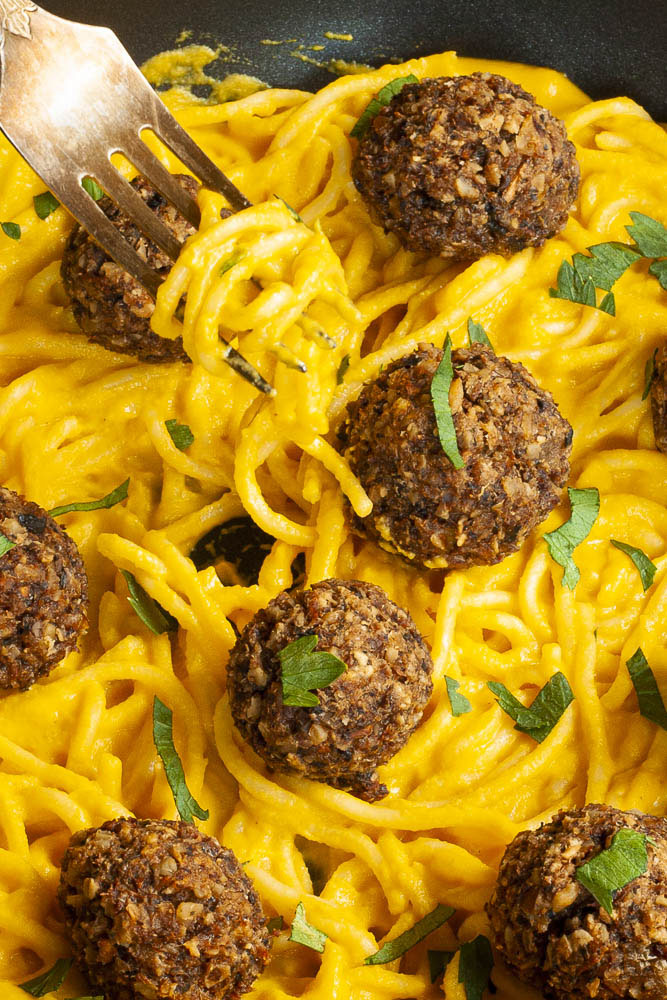 Yellow pasta sauce in a frying pan topped with mushroom meatballs.