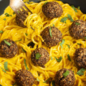 Yellow pasta sauce in a frying pan topped with mushroom meatballs.