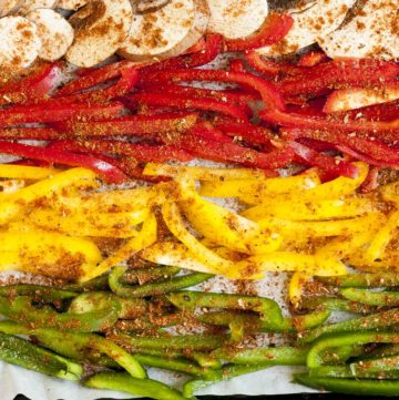Yellow, red and green bell peppers slices seasoned with red spices on a white parchment paper