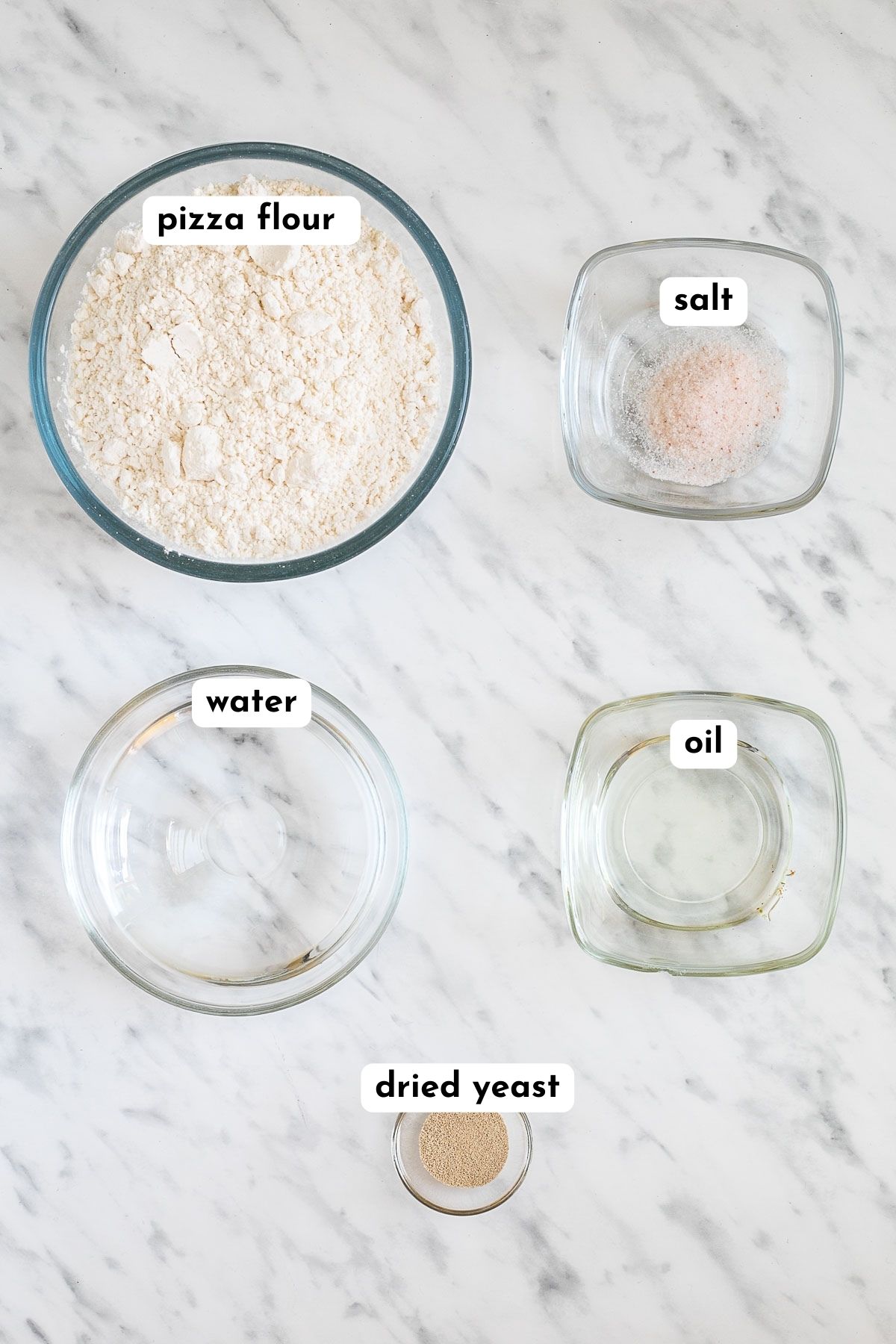 Ingredients of gluten-free pizza crust in small glass bowls: flour, salt, water, oil and dry yeast