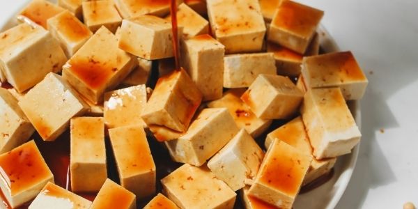 Brown sauce is poured over tofu cubes up close