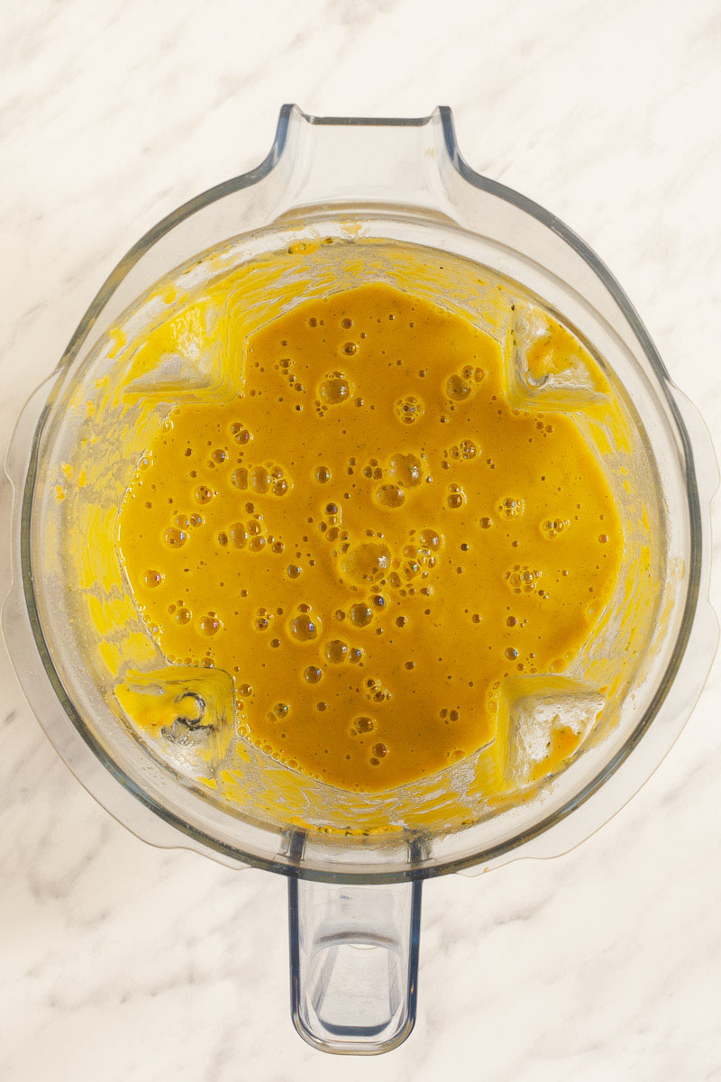 A blender from above showing a yellow cream soup.