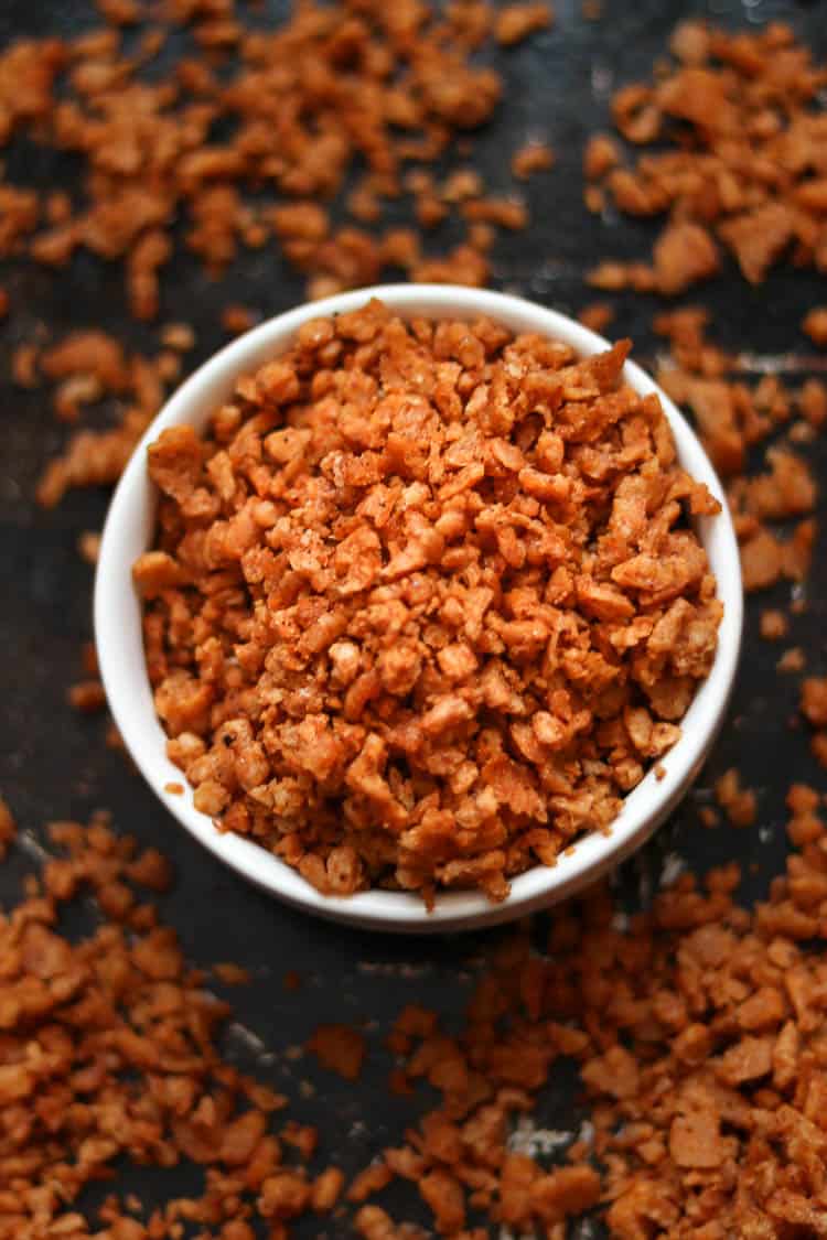 Brown crumbles in a small white bowl and scattered around everywhere