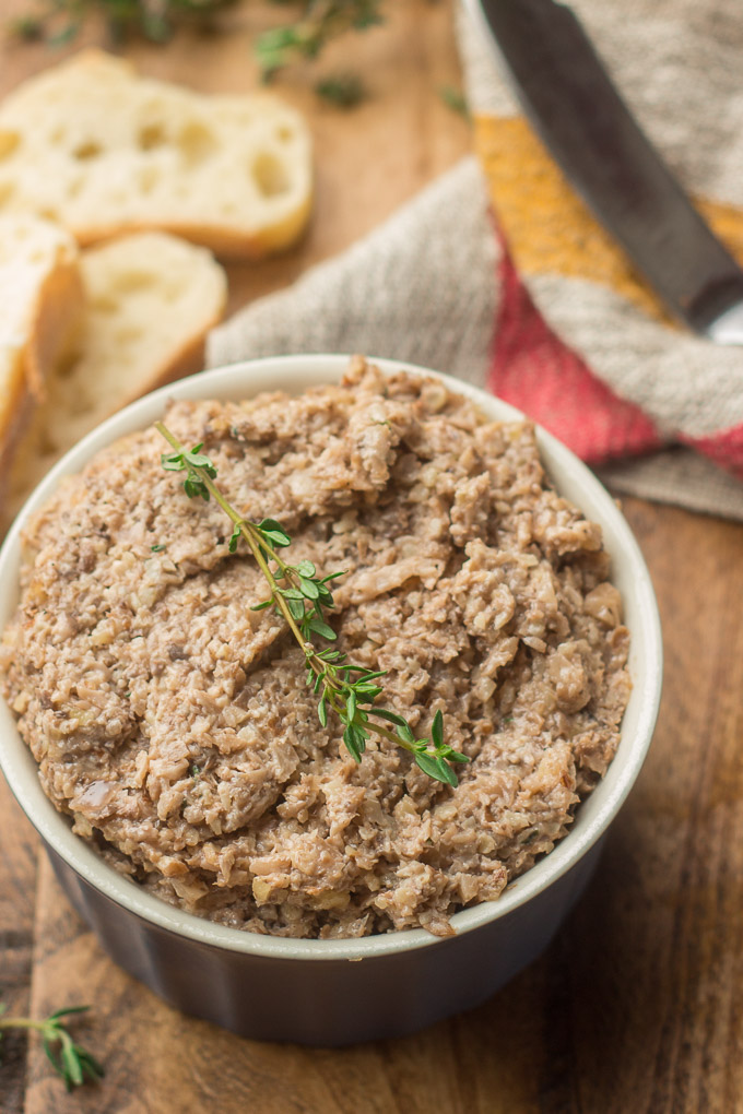 Small white bowl with a brown mush topped with a rosemary twig.