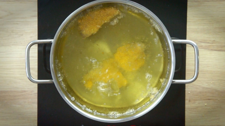 Large pot with yellow liquid and brown nuggets are swimming in it.