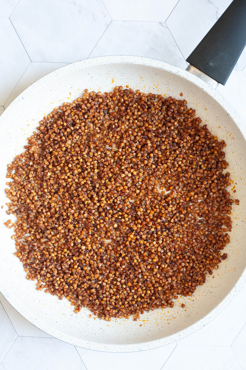 A white frying pan with lots of brown bits.