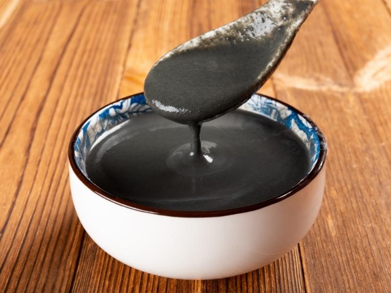 Dark black paste in a small white bowl. A spoon is dipped in it.