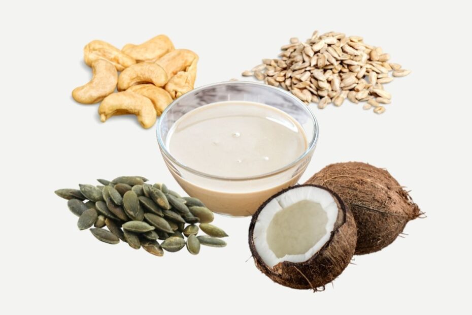 Cashews, coconut, sunflower seeds, pepitas around a small glass bowl with a light brown paste