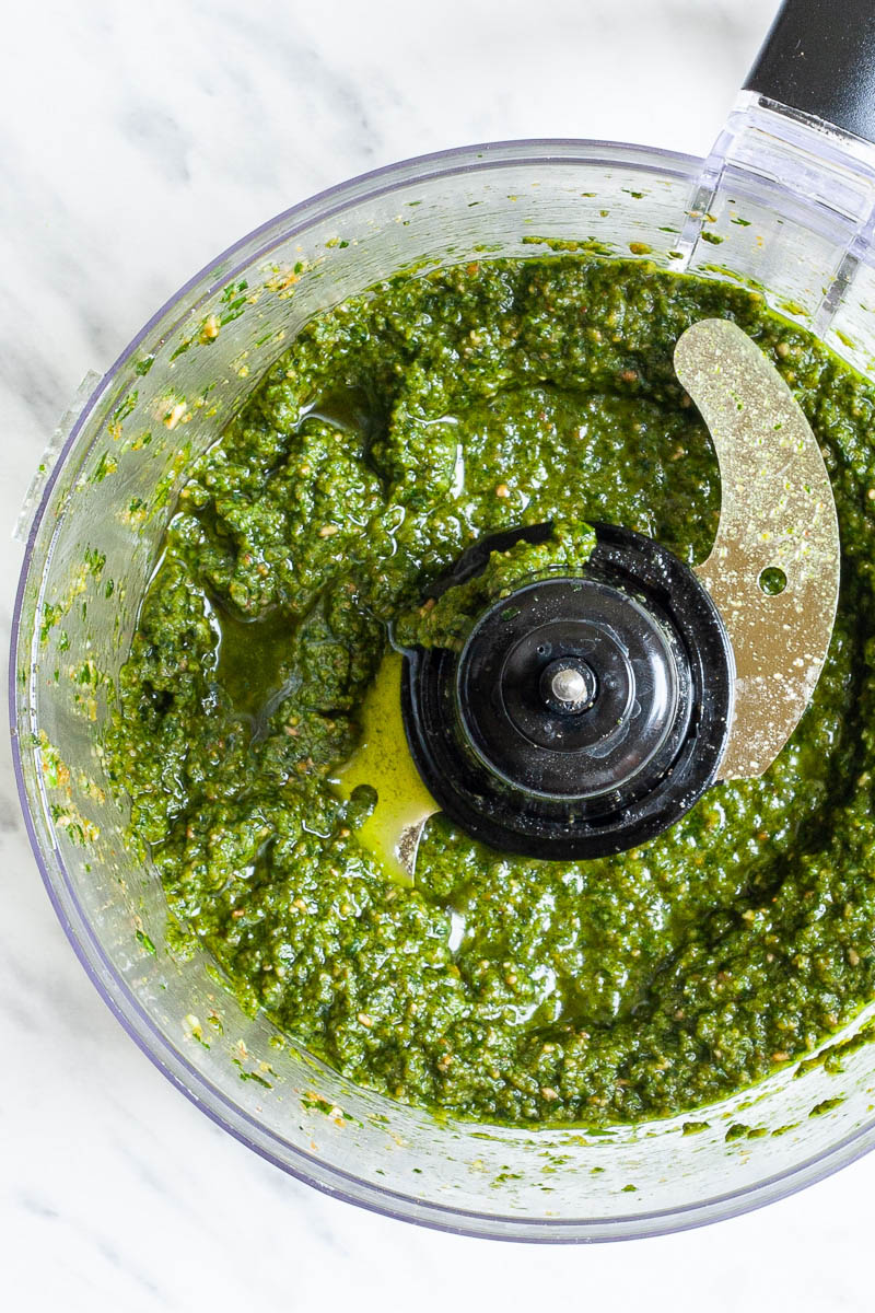 Food processor from above with a chunky green paste.