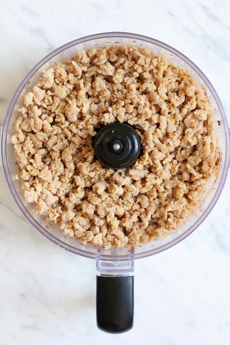 A food processor from above showing soaked TVP from above which has a minced meat like texture