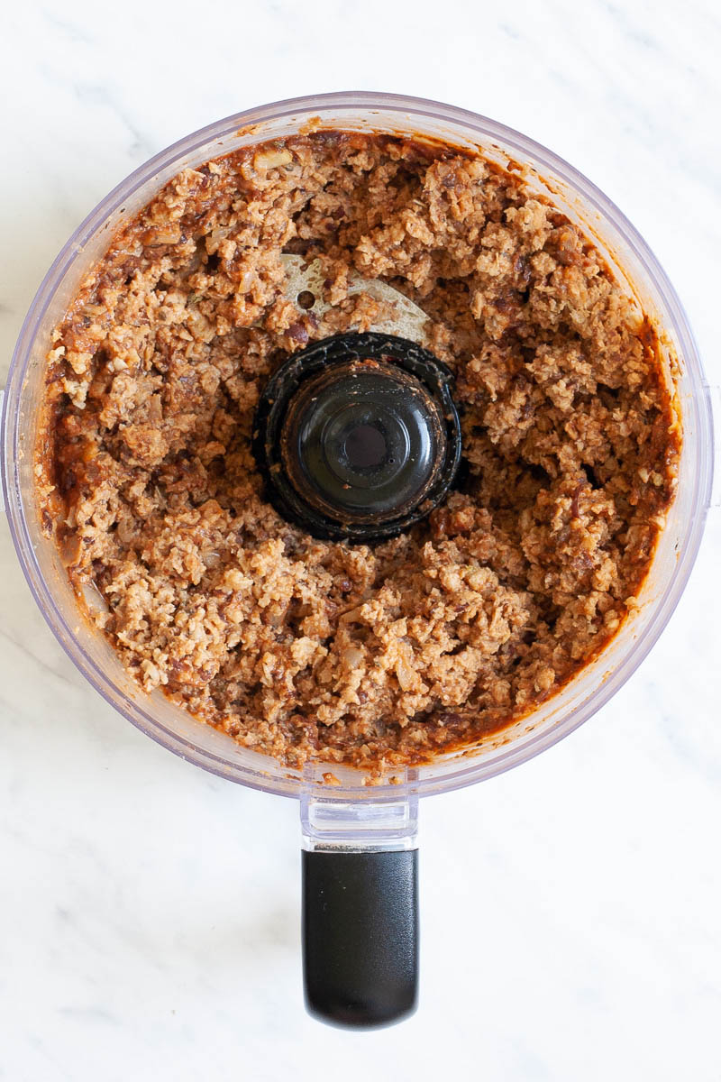 A food processor from above showing a brown crumbly ground meat like texture.