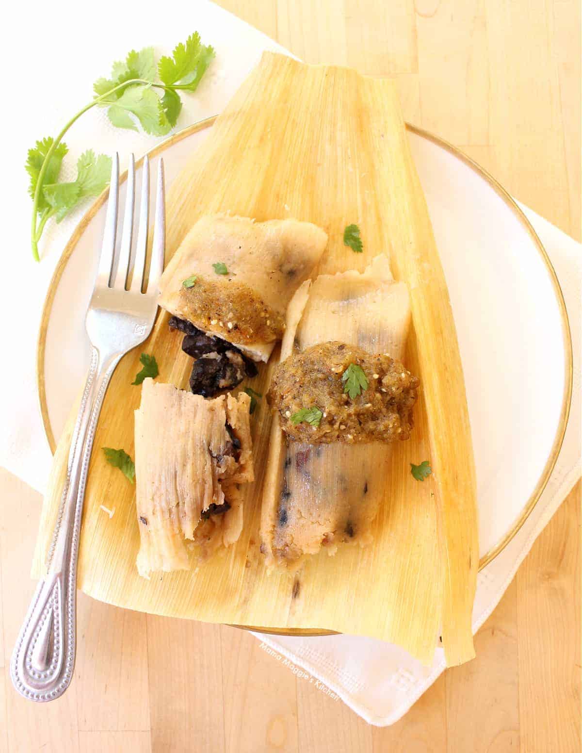 Yellow corn leaf on a white plate filled with a light brown paste and dark mushroom slices