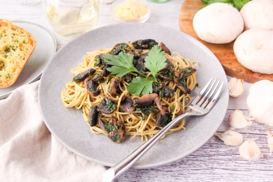 Spaghetti served on a grey plate topped with mushroom slices and parsley