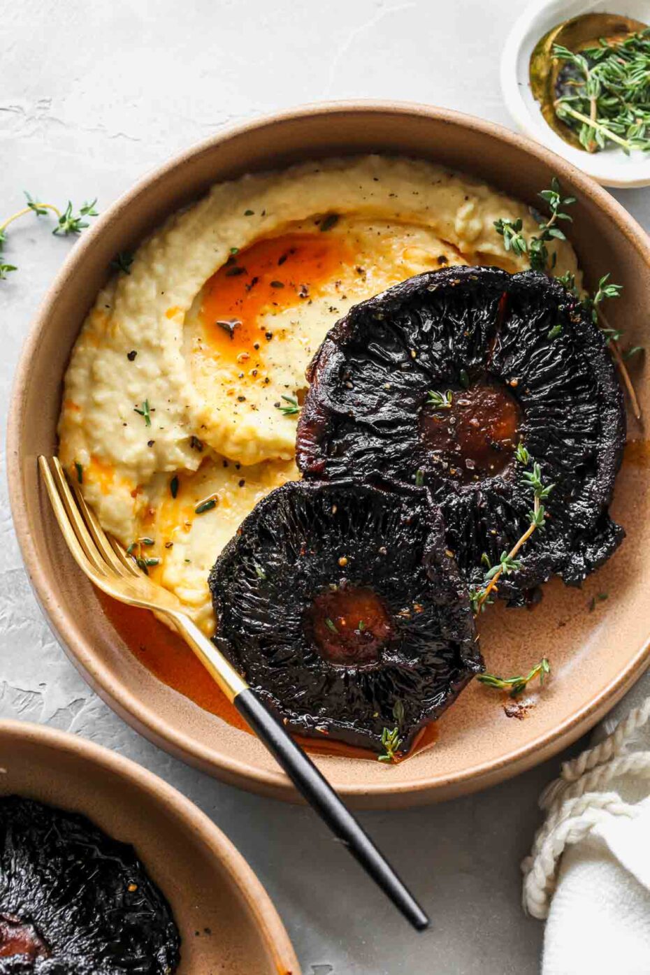 A brown plate from above with dark brown almost black mushroom caps with gills up served with mashed potatoes on the side