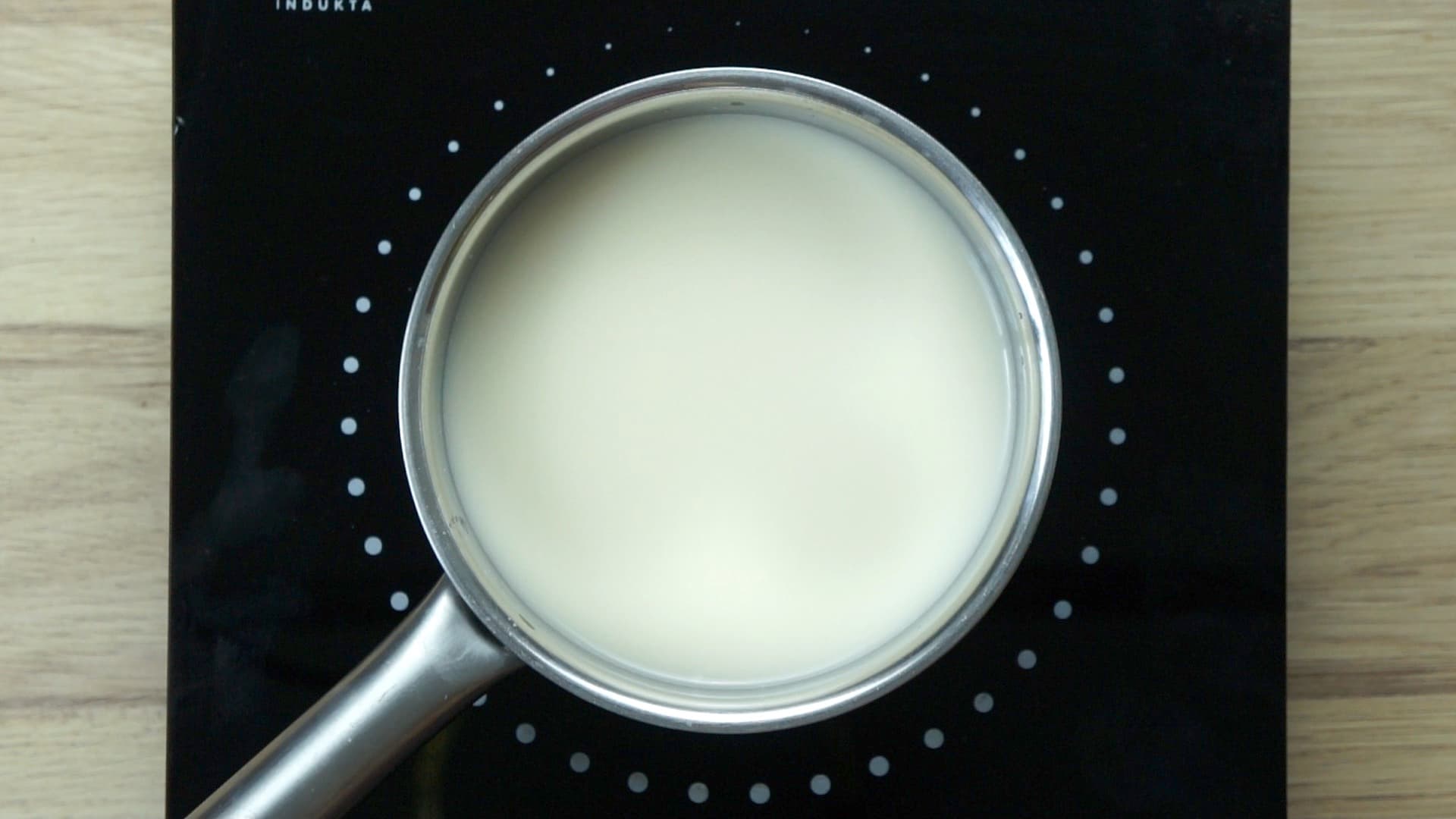 A saucepan on an induction hot plate with white liquid (milk). 