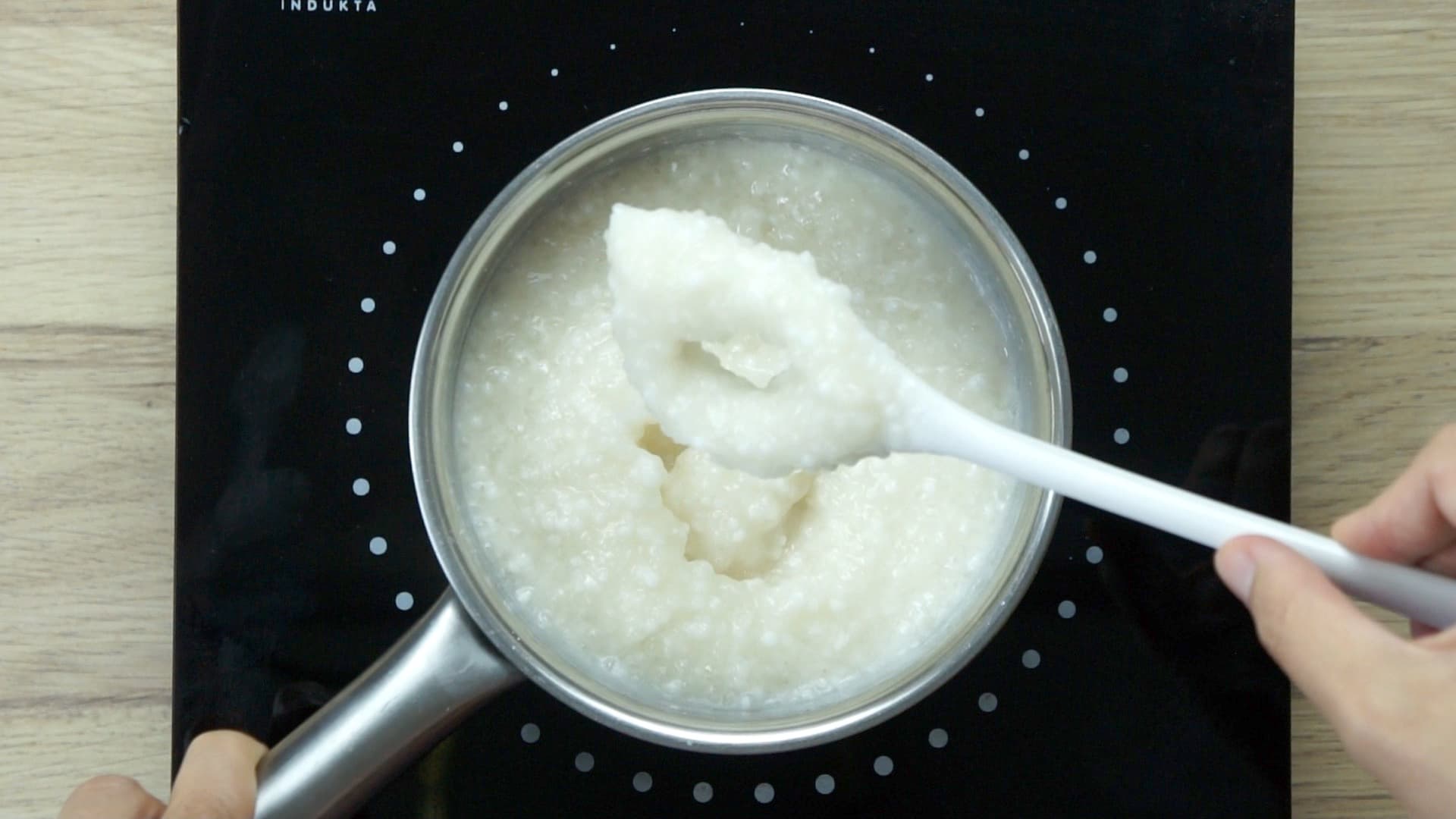 A saucepan on an induction hot plate with a thick white liquid (milk) and small pearls.