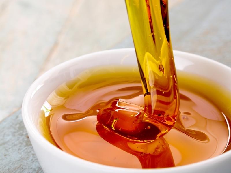 Golden syrup is poured into a small white bowl.