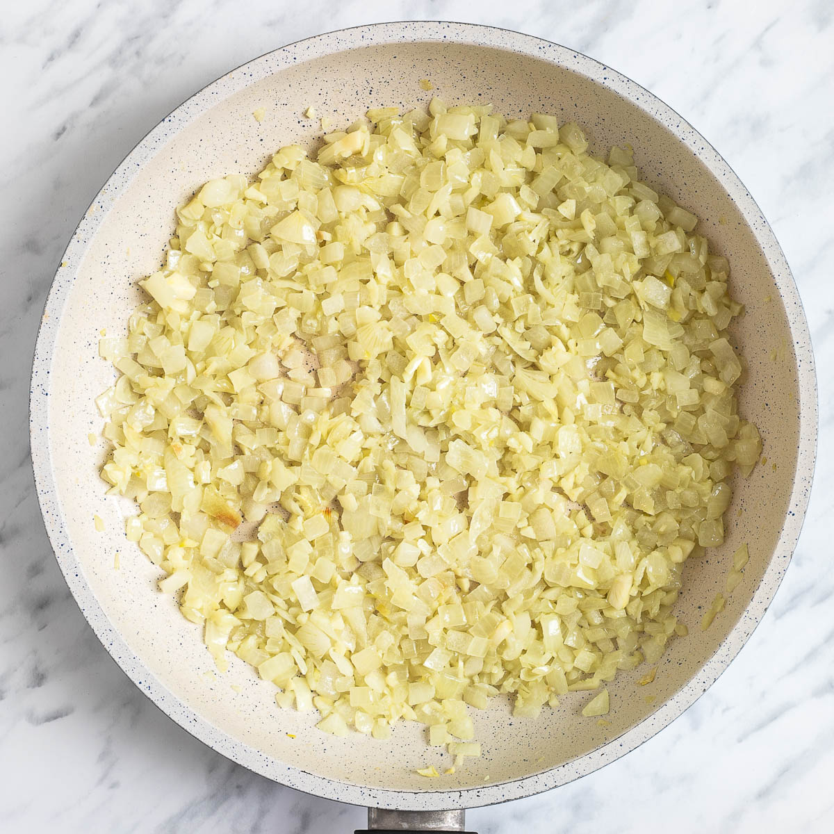 White frying pan with finely chopped onion.