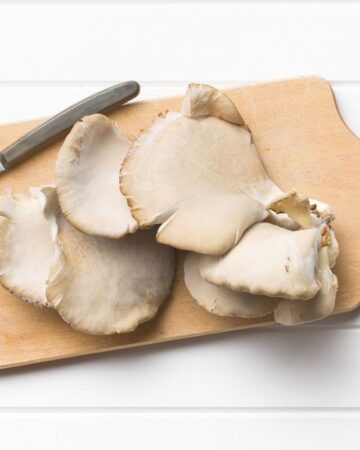 Oyster mushroom on a wooden cutting board with a knife