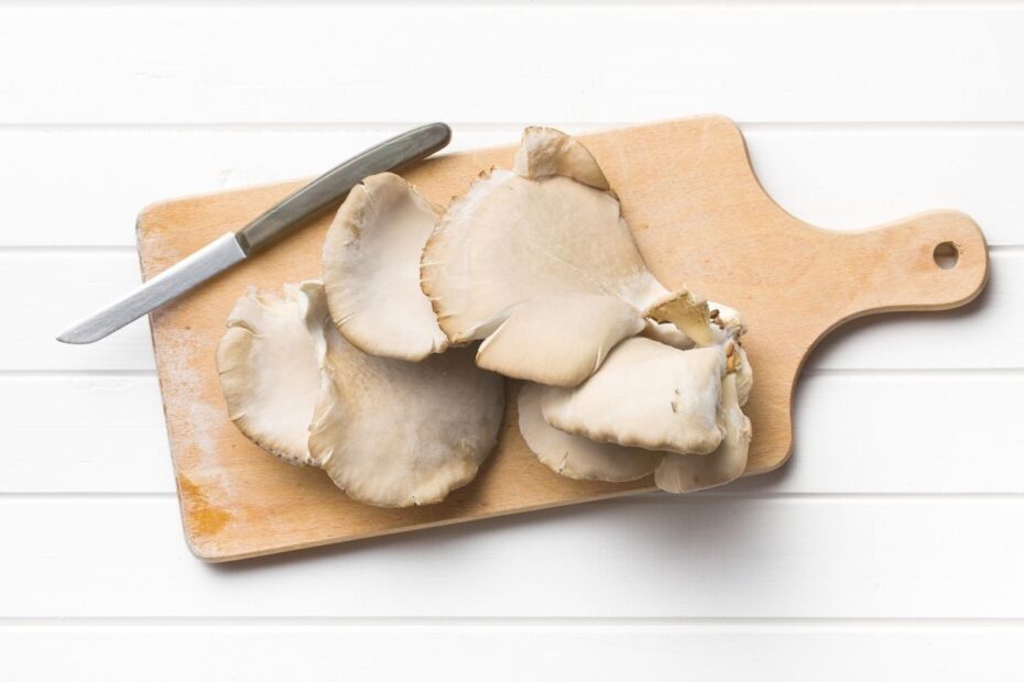 Oyster mushroom on a wooden cutting board with a knife